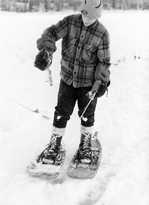 Still wearing his trapper snowshoes the author at age 13 examines a tiny kokanee he caught from Scout Lake in 1971