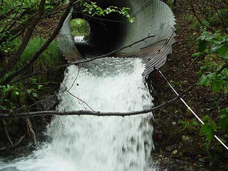This perched culvert in the MatSu Borough was probably installed directly on the stream bed but the outlet has scoured away and now it is perched over four feet above the stream bed Any replacement project will be more difficult as the stream bed is now at a different elevation above and below the road