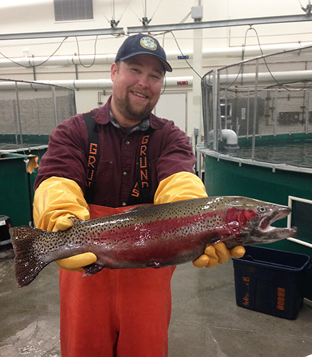 Fish Culturist Jason Woodhull proudly displays a maturing three year old rainbow trout male Photo copyADFampGChuck Pratt