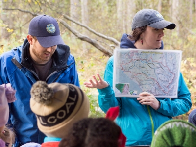 a woman holding a map teaching a class of people