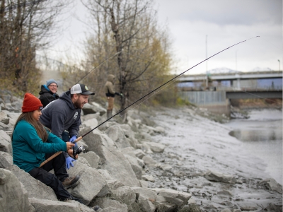 A group of people fishing on the rocky beach of a river